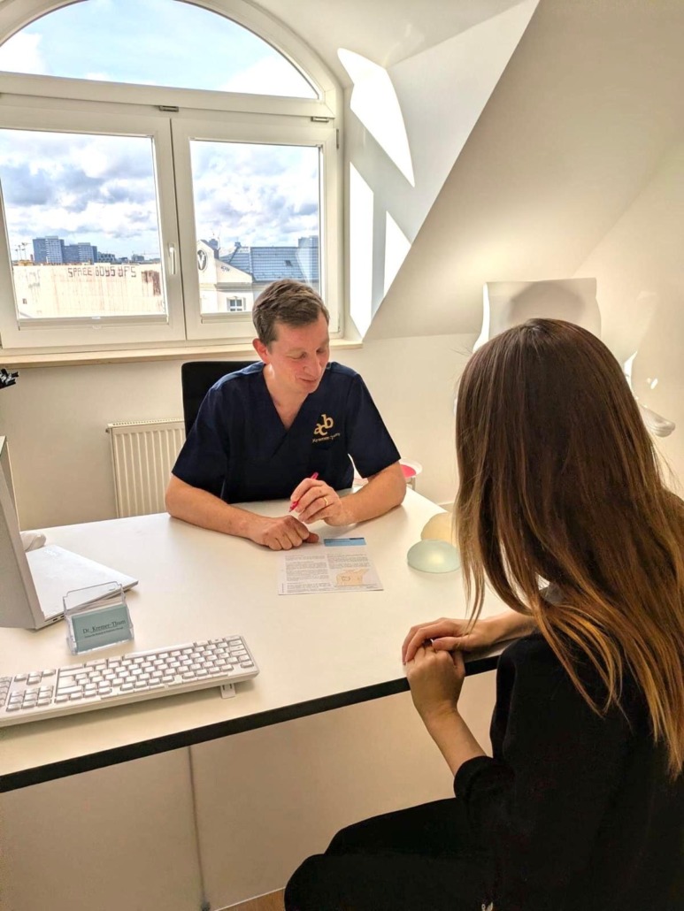 aesthetische-chirurgie-berlin-gesichtsbehandlungen Dr. med. Kremer-Thum sitzt mit einer Patientin am Tisch und berät sie ausführlich zu den Möglichkeiten einer ästhetischen Operation.